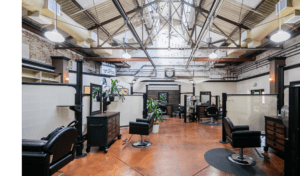 Wide view of salon stations with chairs, high open ceiling with beams