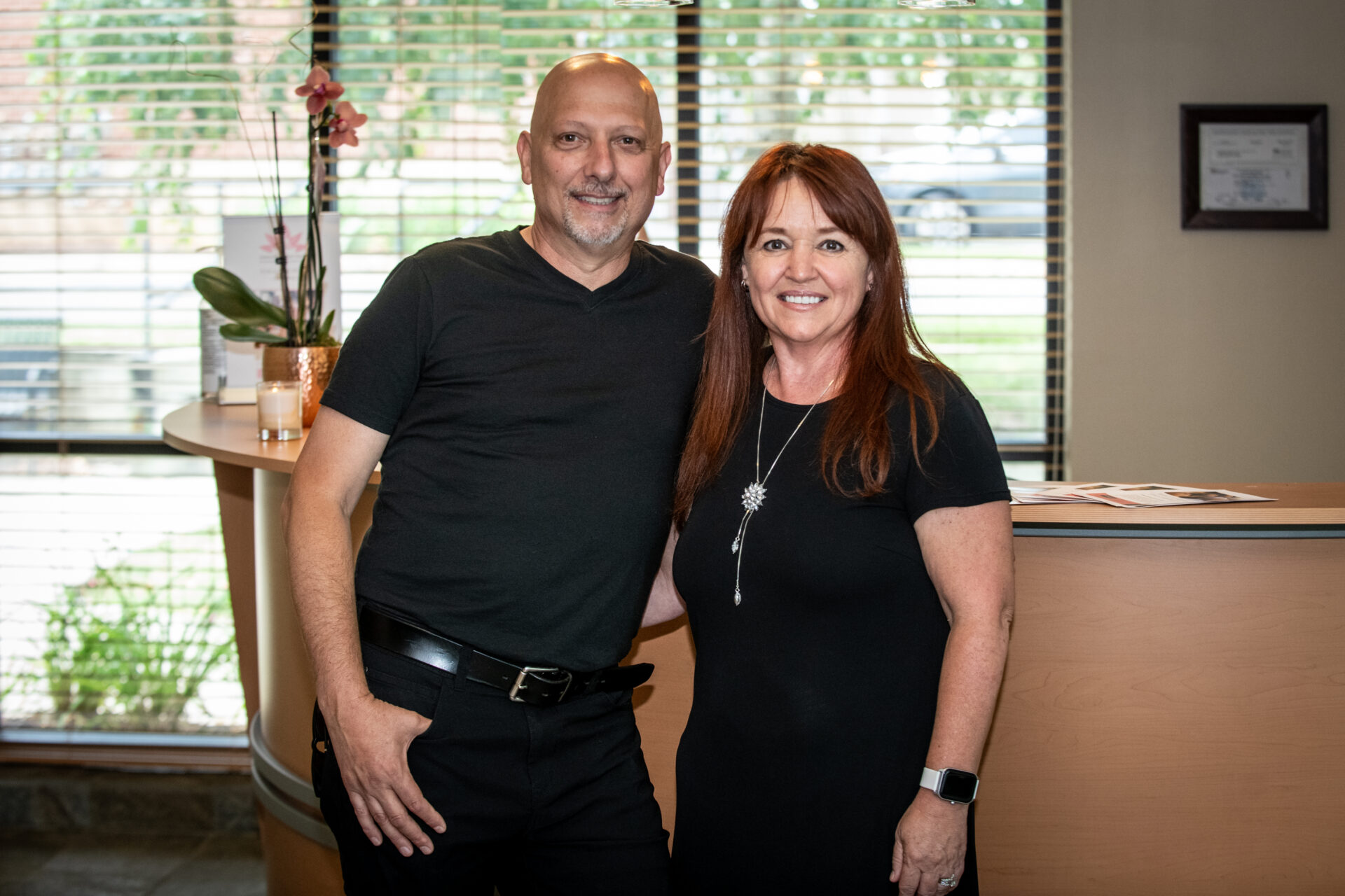 man and woman standing a front desk wearing black