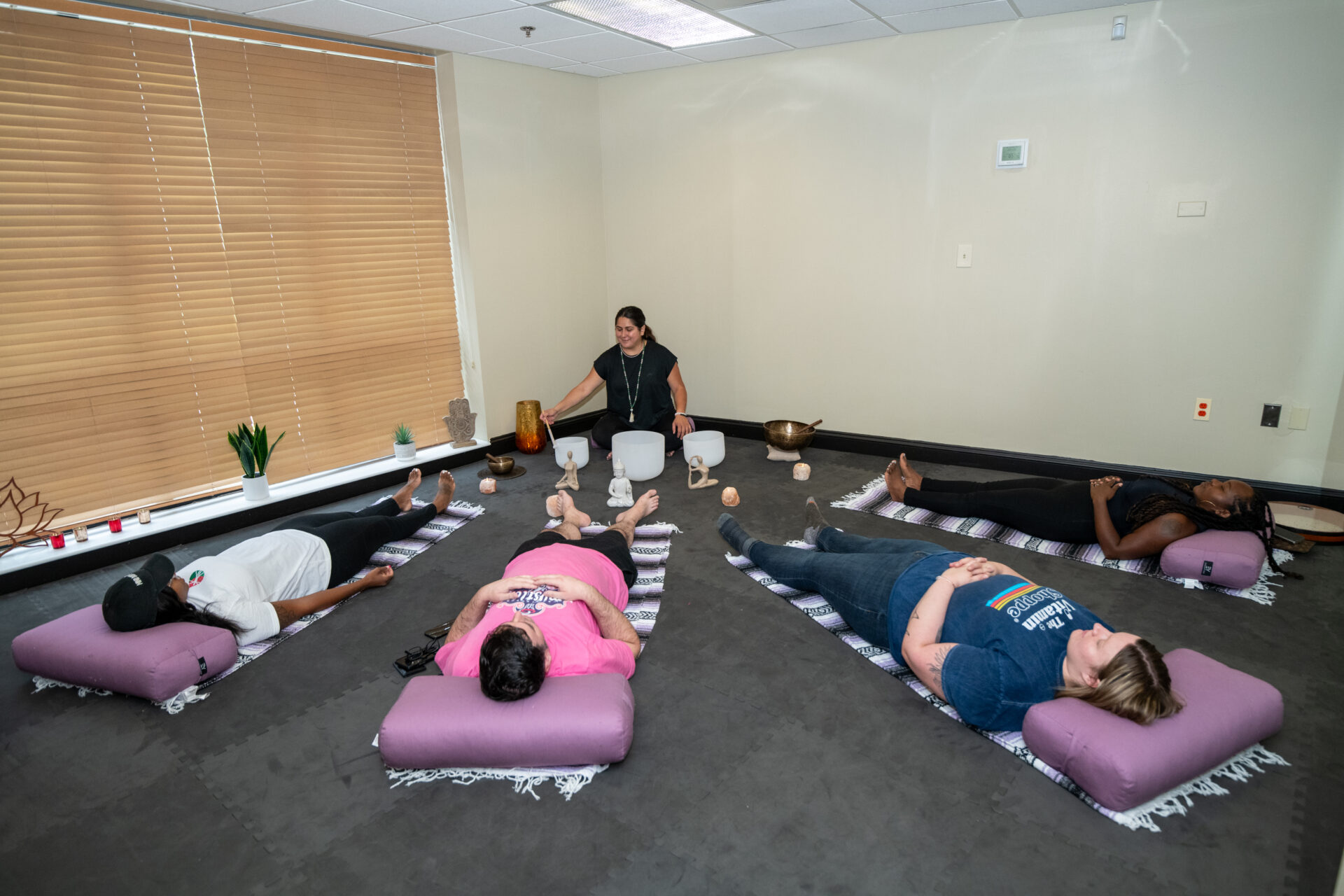 4 people laying down with a yoga instrustor doing sound theropy