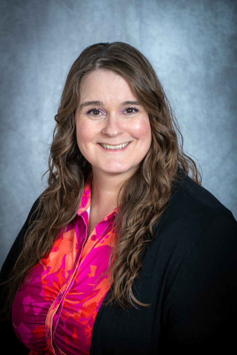 head shot of a women with long hair and pink shirt smiling
